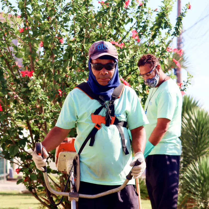 Profissionais da Ativa com roçadeira e equipamento de proteção na manutenção do jardim