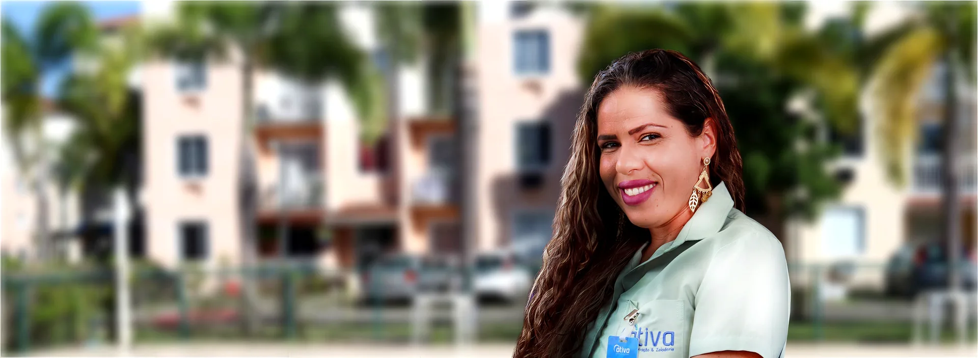 Colaboradora da Ativa sorrindo, de uniforme, em frente a um condomínio